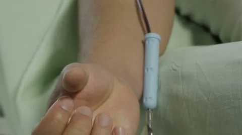 Blood donation.Donor squeezing hand and pumping blood,tilt up to needle in vein. Stock Footage 58607887
