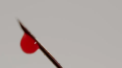Blood drop dripping from a needle tip on white background Stock Footage 329292226
