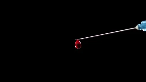 Blood Drop Falling from a Sharp Medical Syringe Needle Against Black Background Stock Footage 331101797