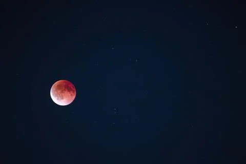 Blood moon during lunar eclipse glowing red in the night sky with visible stars Stock Photos