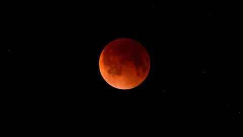Blood moon during a lunar eclipse in the night sky. The moon appears red as i Stock Photos