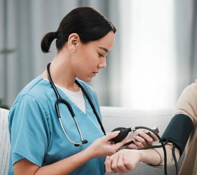 Blood pressure, Asian nurse and patient in a nursing home sofa for health and Stock Photos