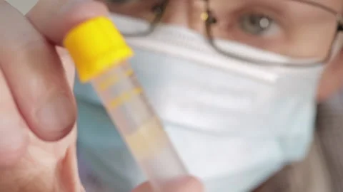 Blood sample collection tube held up by person wearing glasses and a mask Stock Footage 131435080