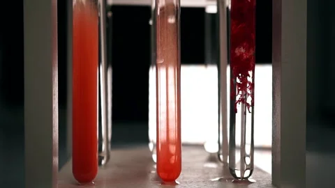 Blood slowly dissolves in a test tube with clear fluid. Slow motion Stock Footage 188749948