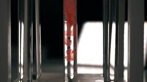 Blood slowly dissolves in a test tube with clear fluid. Slow motion Stock Footage 188750051