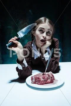 Bloody Halloween theme: crazy girl with a knife, fork and meat Stock Photos