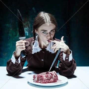 Bloody Halloween theme: crazy girl with a knife, fork and meat Stock Photos