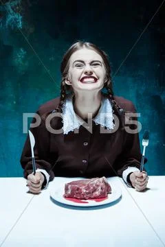 Bloody Halloween theme: crazy girl with a knife, fork and meat Stock Photos