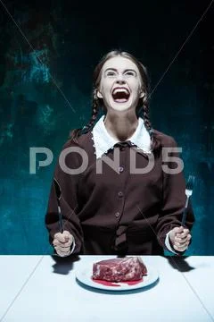 Bloody Halloween theme: crazy girl with a knife, fork and meat Stock Photos