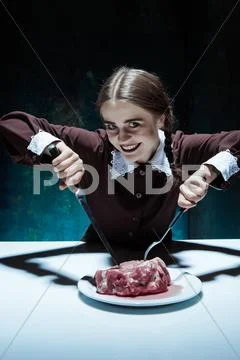 Bloody Halloween theme: crazy girl with a knife, fork and meat Stock Photos