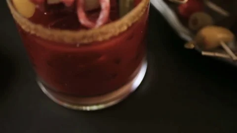 Bloody mary cocktail garnished with celery sticks, olives, and bacon strips. Stock Footage