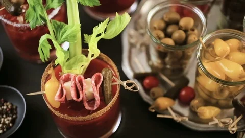 Bloody mary cocktail garnished with celery sticks, olives, and bacon strips. Stock Footage