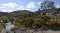 Blooming bushes and abandoned building in sunny hills landscape with river 4k or 4k+ Resolution