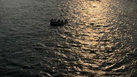 Blow up float floating down the river summer evening, backlit Stockbeeldmateriaal 345095557