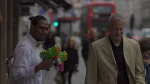 Blowing Bubbles and conducting unseen orchestra in busy city street. Stock Footage 93205953
