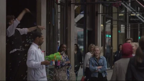 Blowing Bubbles and conducting unseen orchestra in busy city street. Stock Footage 93205984