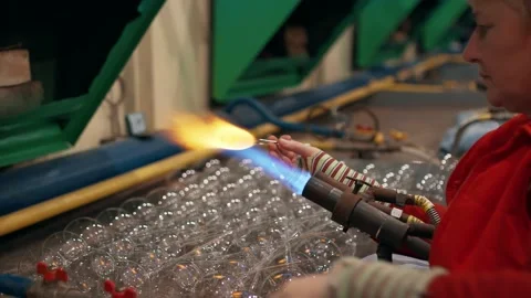 Before blowing Christmas tree decorations worker heats glass with a gas burner Stock Footage 222650833