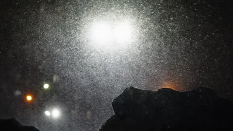 Blowing nighttime snowfall swirling through bright floodlights, with dense Stock Footage 326319351