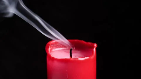 Blowing out a burning red candle. Isolated in front of a black background. Stock Footage 146221895