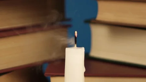 Blowing out a candle on the background of a stack of books Stock Footage 120297446