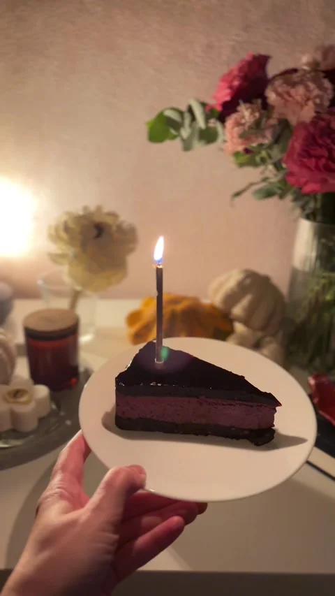 Blowing out a candle on a delicious slice of cake with beautiful flower bouquet Video stock 336259868