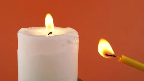 Blowing Out Flame Two Burning Church Candles on a Orange Background. Close up Stock Footage 209125561