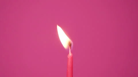 Blowing out one cake candle burning on a pink background. Close up on burning Stock Footage 162860441