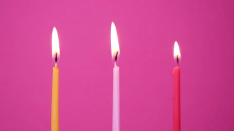 Blowing out Three cake candles burning on a pink background. Close up on blow Stock Footage 160992636
