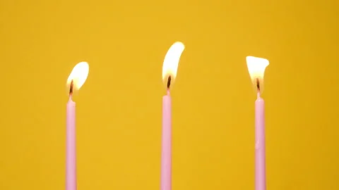 Blowing out Three cake candles burning on a yellow background. Close up on Stock-Footage 160992673