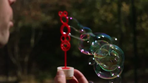Blowing soap bubbles outdoors with bubble wand in garden environment in slow Stock Footage 346070093