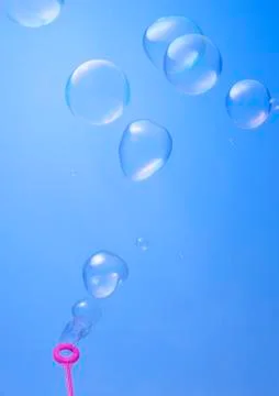 Blowing soup bubbles on blue background Stock Photos