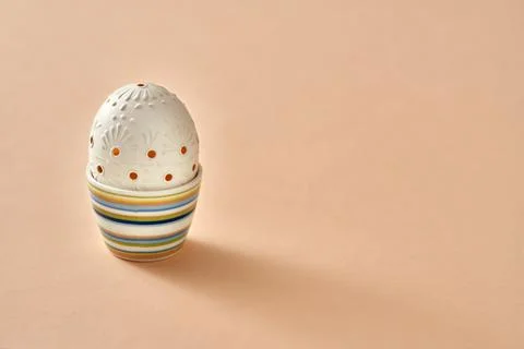 Blown out white Easter egg decorated with wax in a cup on orange pastel backg Foto stock