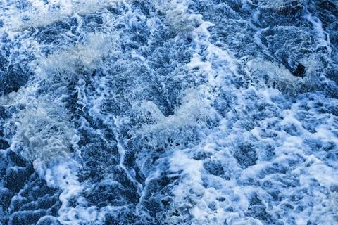 Blu stormy waves creating intricate white foam patterns Stock Photos