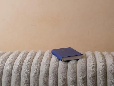 Blue 2025 planner lying on a soft sofa backrest against a light colored wall. Stock Photos