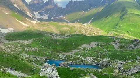 Blue Abudelauri Lake reflecting alpine terrain rests below Chaukhi Mountain Stock Footage 340387461