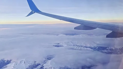 A blue airplane wing is flying through a cloudy sky Stock Footage 277258023