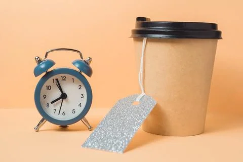 Blue alarm clock sits on a table next to a coffee cup with a silver tag on it Foto stock
