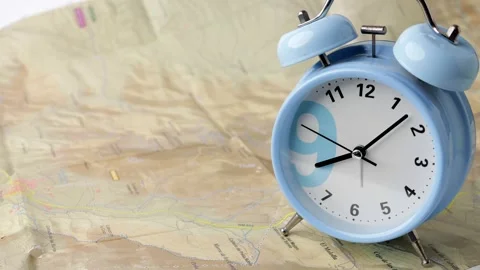 Blue alarm clock ticks steadily on map, with hour hand approaching nine. Sc.. Vidéo 295303319