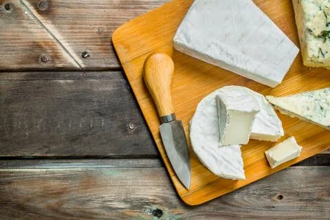 Blue and brie cheese on a chopping Board with a knife. Stock Photos
