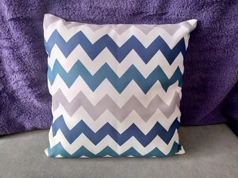 Blue and gray chevron pattern throw pillow on a purple background. Foto stock