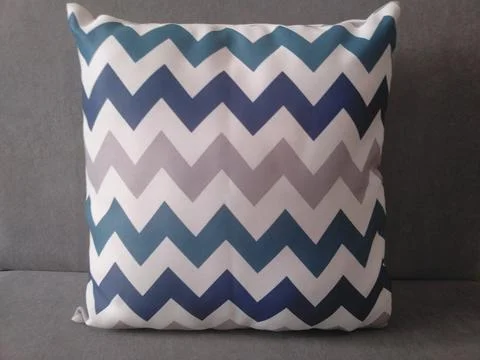 Blue and gray chevron pattern throw pillow on a solid gray background. Stock Photos