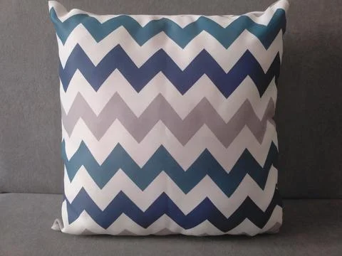 Blue and gray chevron pattern throw pillow on a solid gray background. Foto stock