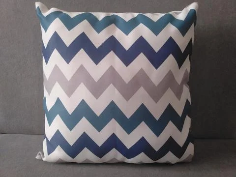 Blue and gray chevron pattern throw pillow on a solid gray background. Stock Photos