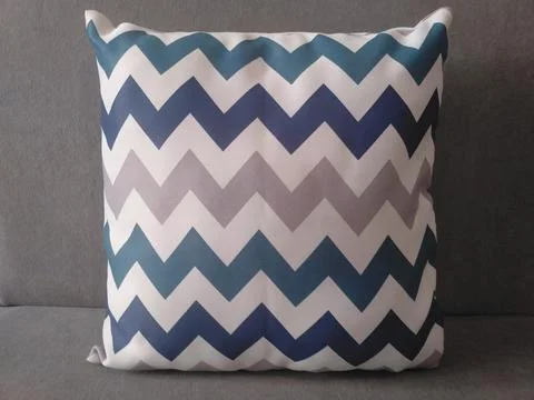 Blue and gray chevron pattern throw pillow on a solid gray background. Stock Photos