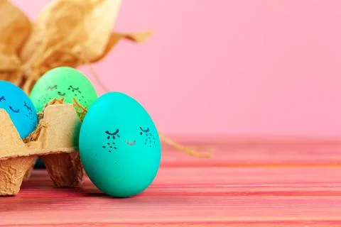 Blue and green colored Easter eggs with drawn funny faces Stock Photos