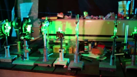Blue and green lasers going through lens on supports on table in laboratory. Stock Footage 69988480