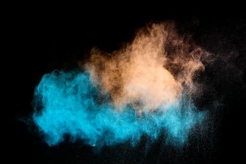 Blue and orange powder exploding on black background 写真素材