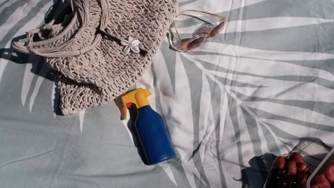 Blue and orange sunscreen bottles land on a beach towel next to a bag 스톡 동영상 313290678