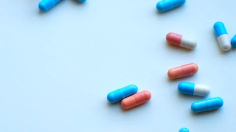 Blue and pink capsules falling on a white background Stock Footage 311941479