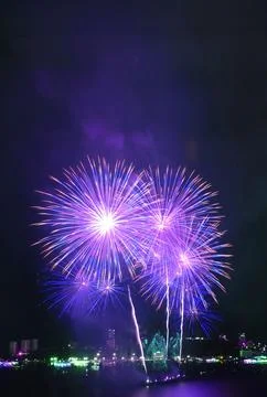 Blue and purple fireworks exploding into the night sky over the harbor Foto stock